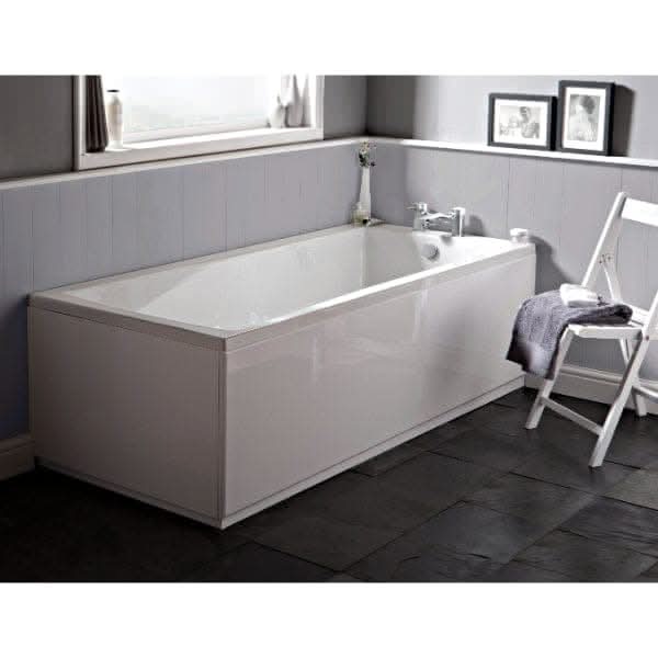 A modern Nuie Linton Single Ended Bath - White by Nuie in a bathroom with light gray walls, a curtained window, framed pictures, and a white folding chair on dark tiled flooring.