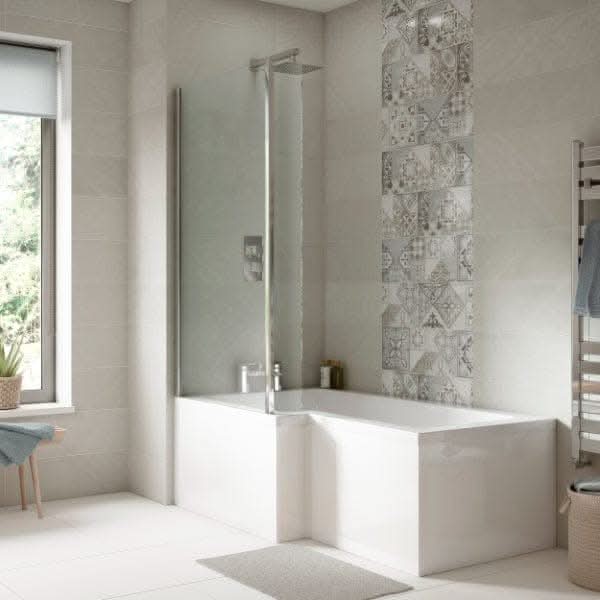 Modern bathroom featuring the Nuie Square B Shape Shower Bath With Screen And Front Panel in white, stylish patterned tile accent wall, grey tiled walls and floor, a window with a blind, and a heated towel rail.