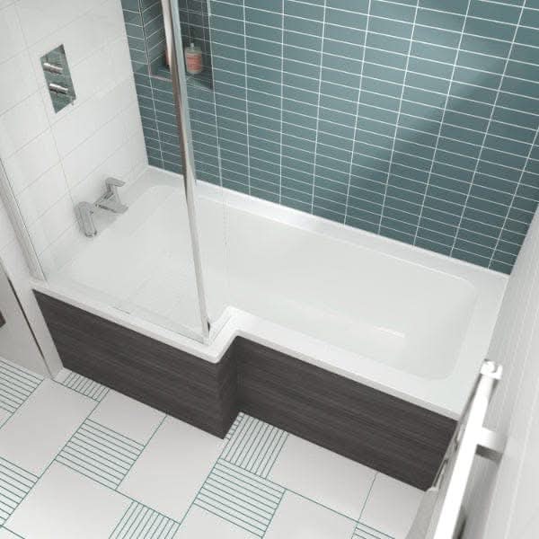 Modern bathroom with a Nuie Square L Shape Shower Bath in white, blue-green subway tile backsplash, patterned floor tiles, glass shower screen, and dark wood paneling around the tub.