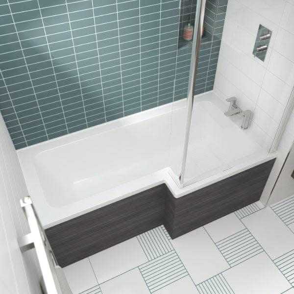 Modern bathroom with a Nuie Square L Shape Shower Bath in white, complemented by a dark wood panel, glass shower screen, teal subway tiles, patterned white and teal floor tiles, and a bottle on the built-in shower shelf.