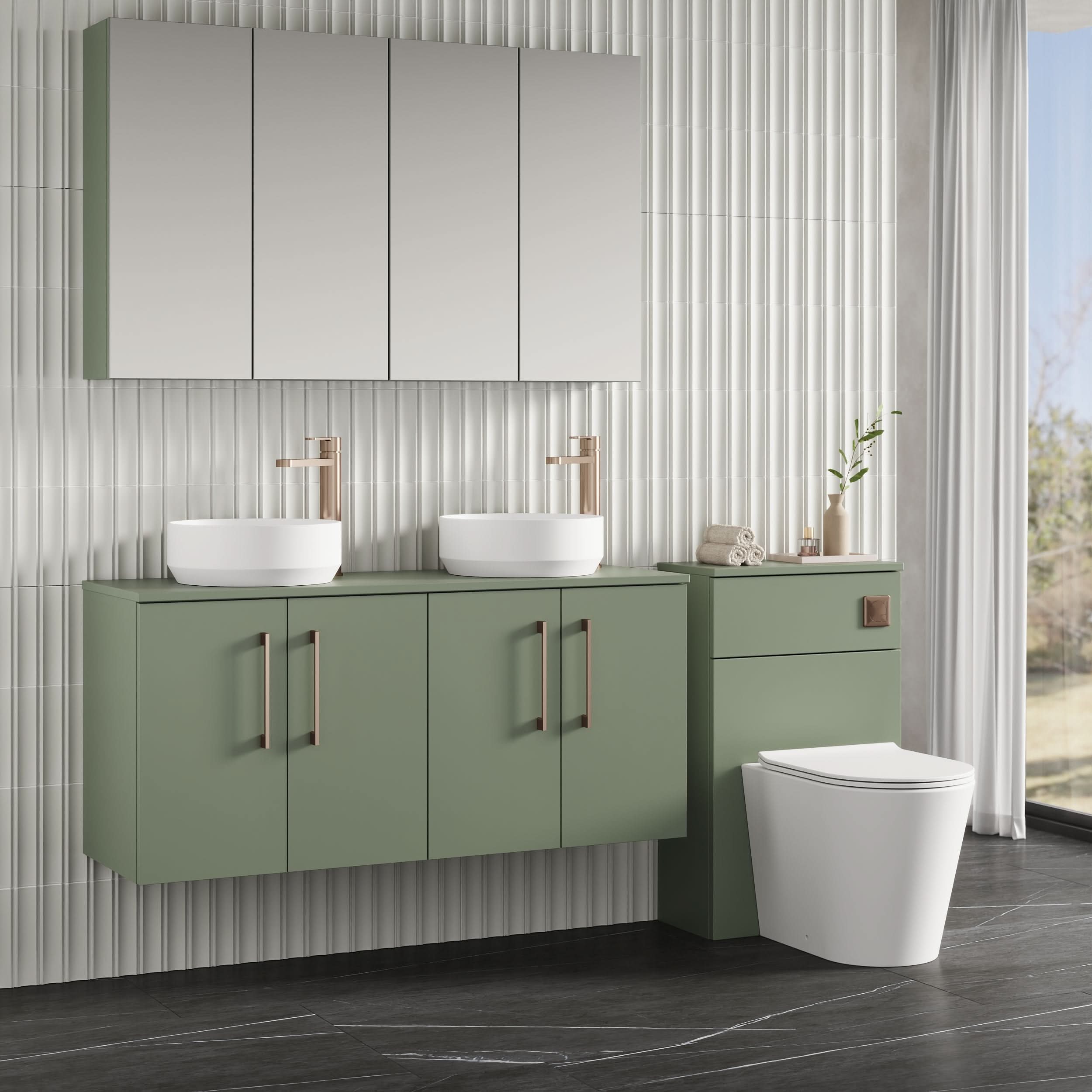 Modern bathroom featuring a green Nuie Arno 4 Door Wall Hung Vanity Unit With Worktop (1200mm), two vessel sinks with gold faucets, wall-mounted mirrored cabinet, white toilet, light vertical textured tiles, and natural light from the right.