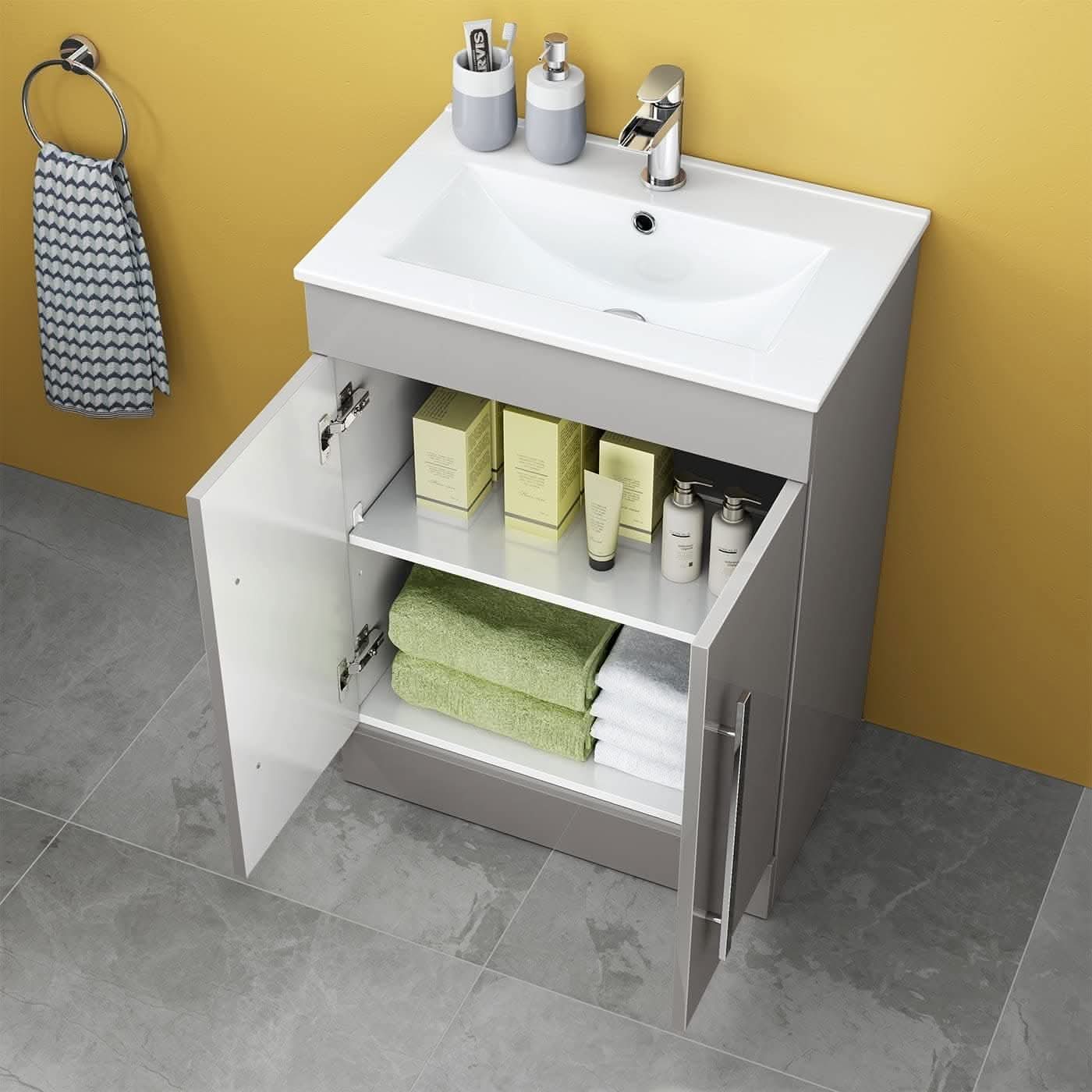 The iBathUK Avon 2 Door Floorstanding Vanity Unit With Basin (615mm x 815mm, 1 Tap Hole) features a white sink, silver faucet, and open doors showing towels and toiletries, standing out against a yellow wall and gray tiled floor.
