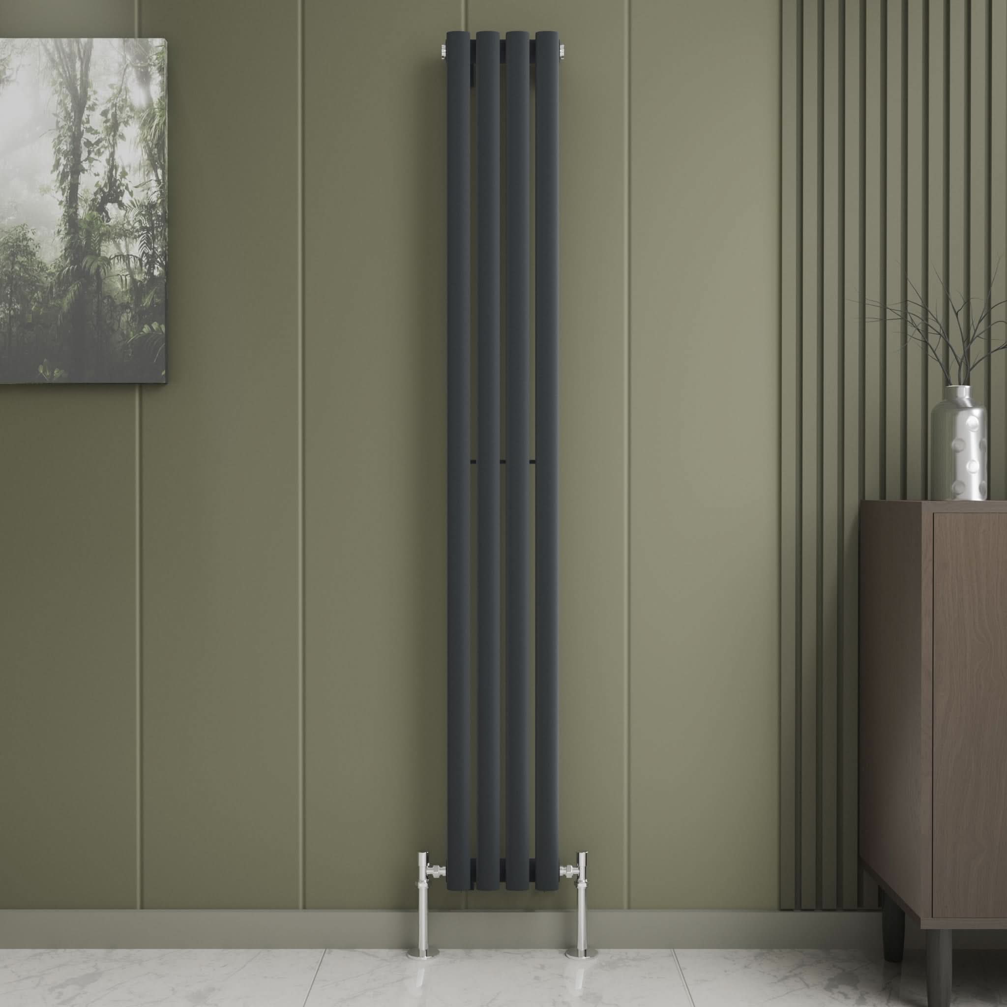 The Princia Vertical Single Oval Panel Radiator by iBathUK in matte black is mounted on an olive green wall next to modern wood paneling and a brown cabinet, with a vase plant and nature artwork completing the minimalist designer look.
