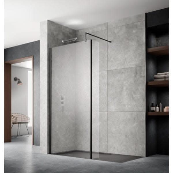 Modern contemporary bathroom with a walk-in glass shower featuring the Nuie Wetroom Return Screen by Nuie in a black metal frame, large gray tile walls, open shelving on the right, and a glimpse of a chair through a nearby doorway.